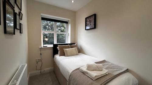 a small bedroom with a bed and a window at Newbuild, 3 Bedroom house with free parking in Aldershot