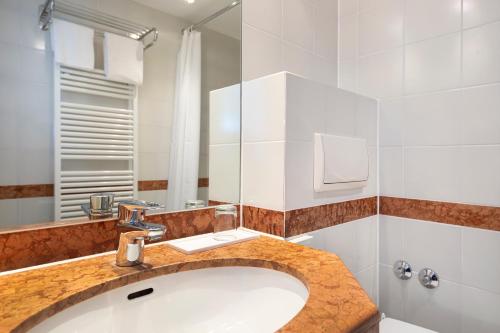 a bathroom with a sink and a mirror at ACHAT Hotel Magdeburg in Magdeburg