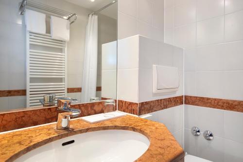ein Bad mit einem Waschbecken und einem Spiegel in der Unterkunft ACHAT Hotel Magdeburg in Magdeburg