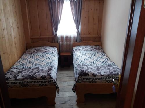 twee bedden in een kleine kamer met een raam bij Guesthouse Solomon in Chvibiani