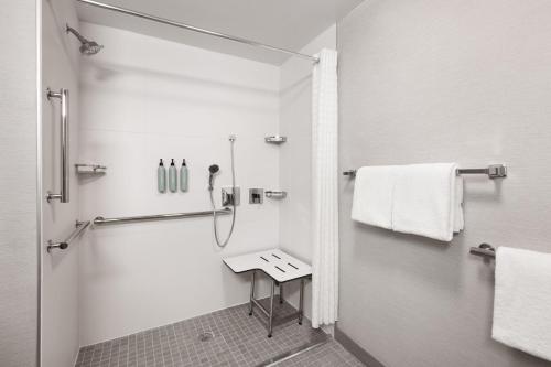 a white bathroom with a shower and a stool at Courtyard by Marriott Memphis Airport in Memphis