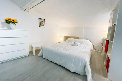 - une chambre blanche avec un lit et un vase de fleurs dans l'établissement #EH Le Rousseau, à Grenoble