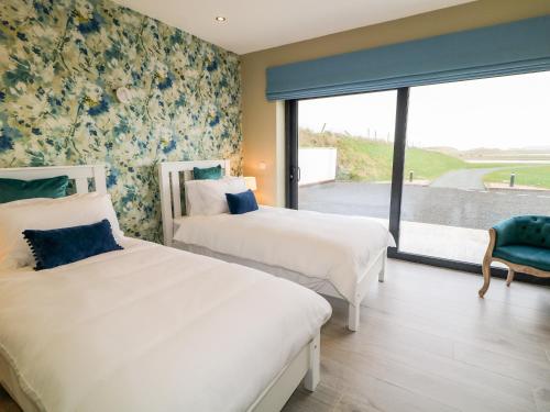 two beds in a hotel room with a window at The Beachhouse in Cashel Hill