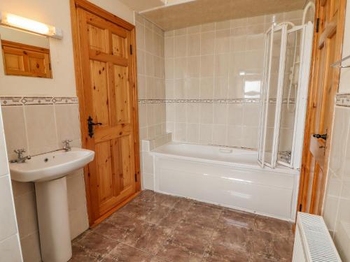 La salle de bains est pourvue d'une baignoire blanche et d'un lavabo. dans l'établissement Clogher Cottage, à Doonbeg