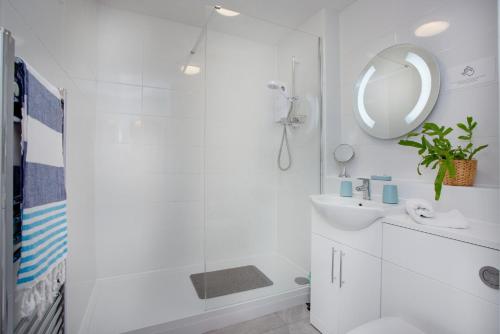 a white bathroom with a sink and a mirror at The Sail Loft in Sidmouth