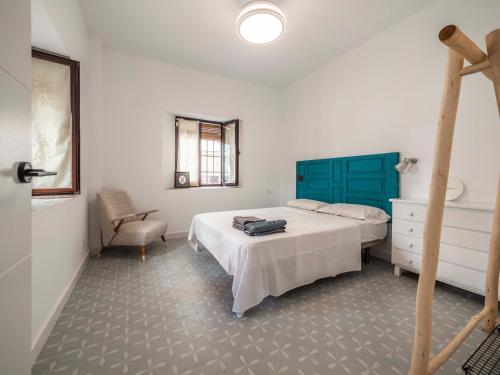 a bedroom with a bed with a blue headboard and a chair at Morales 8 - Bajo céntrico y acogedor con entrada independiente in Talavera de la Reina