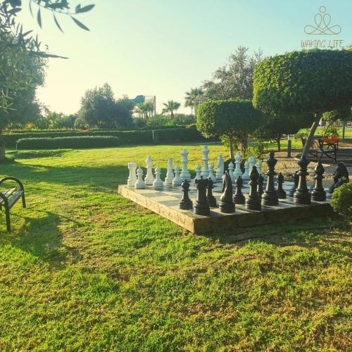 a giant chessboard in a park with a bench at Great seaview appartments in Thalassa in Vokolidha