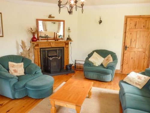 a living room with two blue chairs and a fireplace at Reeks Cottage in Killorglin