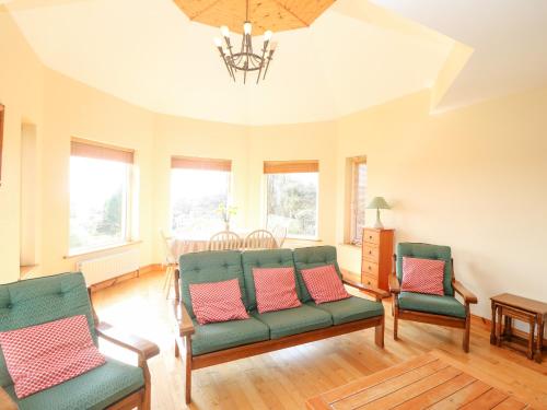 a living room with green chairs and a table at Bluebell House and Gardens in Rossbrin