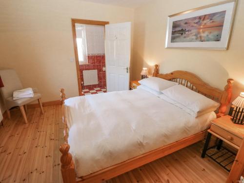 a bedroom with a large bed with a wooden floor at Bluebell House and Gardens in Rossbrin