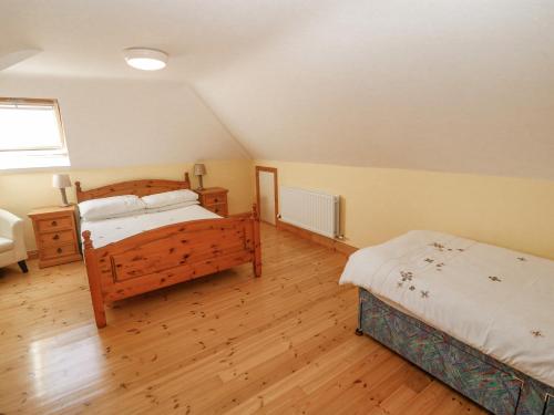 a bedroom with two beds and wooden floors at Bluebell House and Gardens in Rossbrin