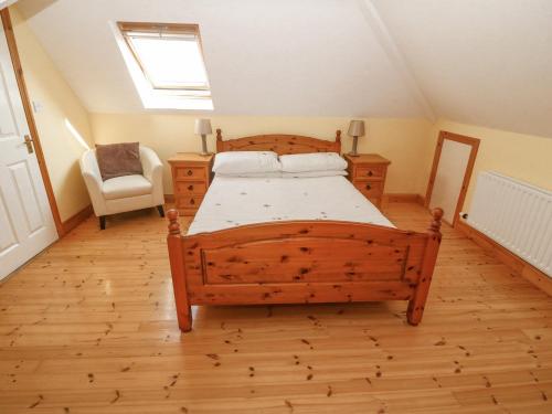 a bedroom with a wooden bed and a chair at Bluebell House and Gardens in Rossbrin