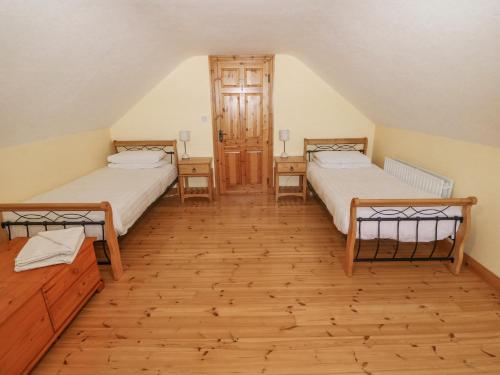 two beds in a room with wooden floors at Bluebell House and Gardens in Rossbrin