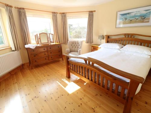 a bedroom with a large bed and a chair at Bluebell House and Gardens in Rossbrin