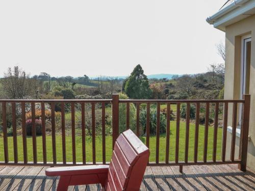 a red bench sitting on a balcony with a view of a yard at Bluebell House and Gardens in Rossbrin