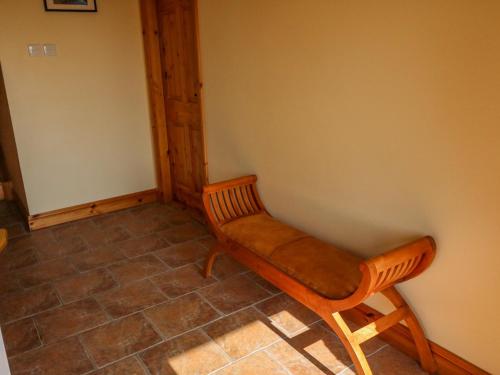 a wooden chair sitting in the corner of a room at Bluebell House and Gardens in Rossbrin