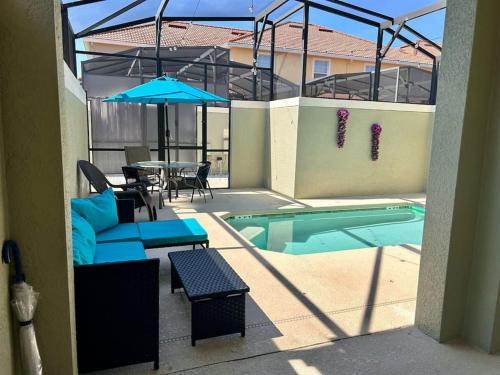 eine Terrasse mit einem Tisch und einem Sonnenschirm neben einem Pool in der Unterkunft Resort style home across from the clubhouse. in Kissimmee