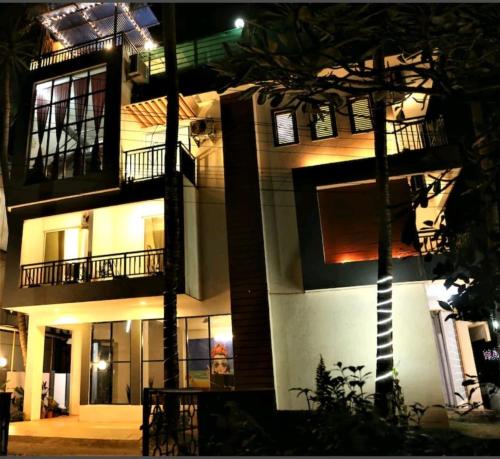 a building at night with a palm tree in front of it at Bella vista in Candolim