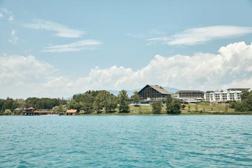 a view of the lake with buildings in the background at Hotel Karnerhof in Egg am Faaker See