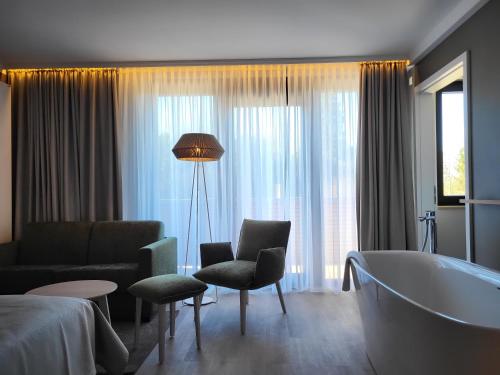a hotel room with a tub and a couch and a bed at Landhotel Rittmeister & Kräuter-SPA Adults Only in Rostock
