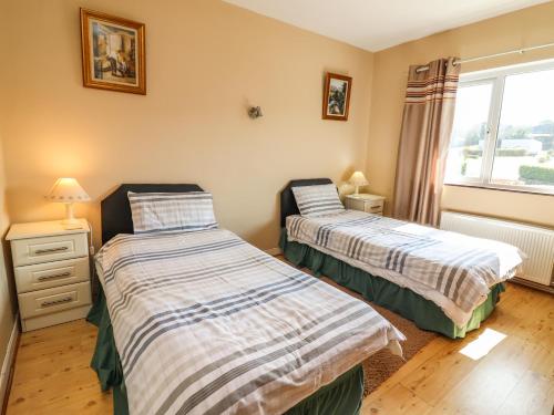 two beds in a room with a window at Gap of Dunloe in Derrylea