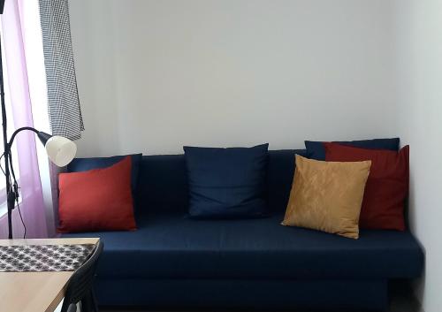 un divano blu con cuscini di colore diverso di HOLA Apartamenty Narutowicza a Łódź