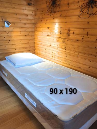 un lit dans une chambre avec un mur en bois dans l'établissement les Genêts, à La Bresse