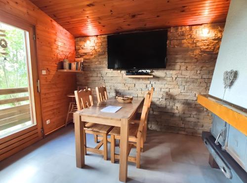 uma sala de jantar com uma mesa e uma televisão numa parede de tijolos em les Genêts em La Bresse