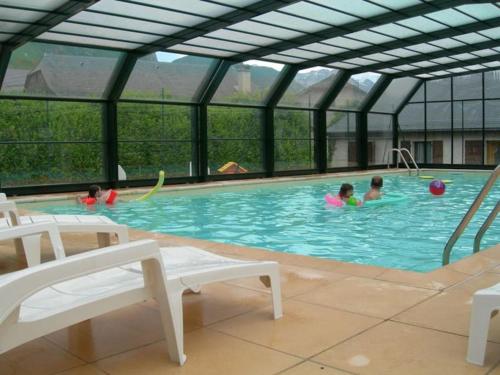 three children swimming in a pool in a building at La Campana 104 in Bielle