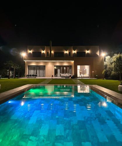 een zwembad voor een huis 's nachts bij Villa Jne Marrakech in Oulad Mazoug
