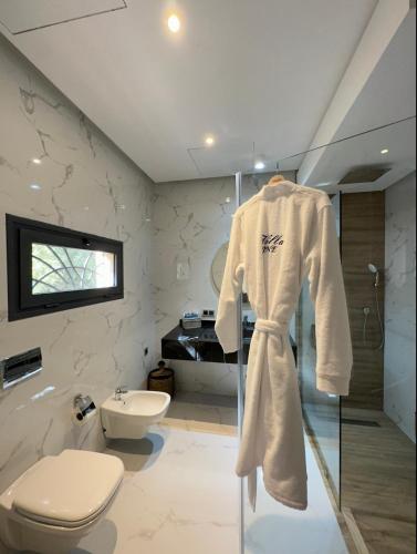 a bathroom with a toilet and a robe on a rack at Villa Jne Marrakech in Oulad Mazoug