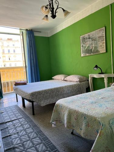Cette chambre verte comprend 2 lits et une fenêtre. dans l'établissement B&B MIRAGLIA, à Naples