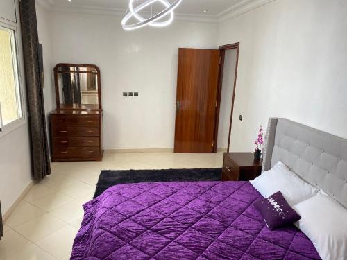a bedroom with a purple bed and a dresser at Huge 4 bedroom Condo 2 min walking to TGV train in Kenitra