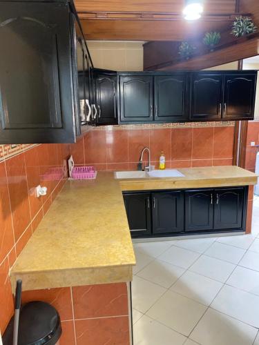 a kitchen with black cabinets and a sink at Huge 4 bedroom Condo 2 min walking to TGV train in Kenitra