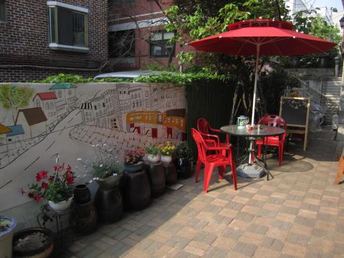 een patio met een tafel en stoelen en een parasol bij Appletree Guesthouse in Seoul