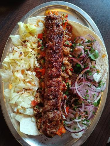 a plate of food with meat and coleslaw and onions at Hotel Paffhausen in Wirges
