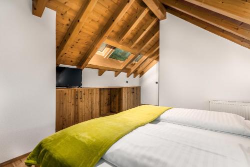 a bedroom with a bed with a yellow blanket on it at Apartments Perfila Falkenauge in Valdaora