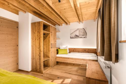 ein kleines Zimmer mit Holzböden und einem Bett in der Ecke. in der Unterkunft Apartments Perfila Dolomitenblick in Olang