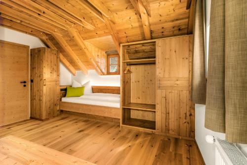 a room with a bed and wooden walls and wooden floors at Apartments Perfila Morgenrot in Valdaora