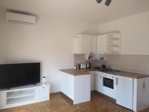 a kitchen with white cabinets and a flat screen tv at Apartments Netty in Dramalj