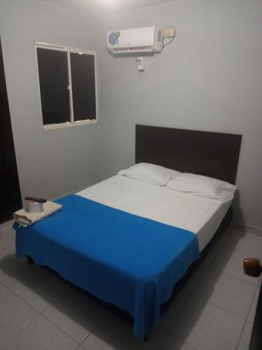 a bedroom with a bed with a blue blanket and a window at Comfort inn in Maicao