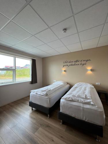2 camas en una habitación con un cartel en el techo en Vagnsstadir Guesthouse, en Borgarhöfn