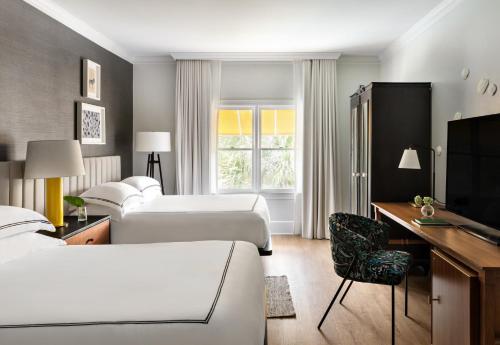 a hotel room with beds and a desk and a tv at Kimpton Brice Hotel by IHG in Savannah