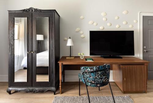 a bedroom with a desk with a television and a mirror at Kimpton Brice Hotel by IHG in Savannah