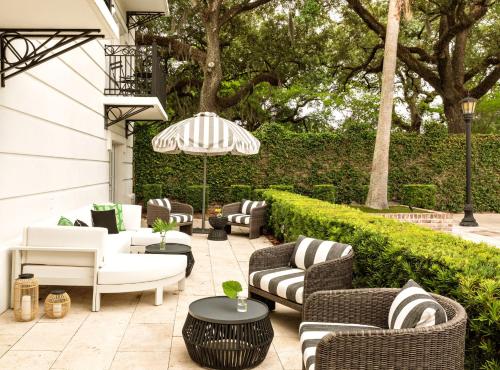a patio with couches and tables and an umbrella at Kimpton Brice Hotel by IHG in Savannah
