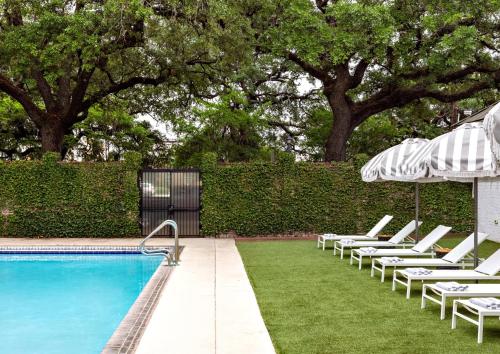 a row of chairs and an umbrella next to a swimming pool at Kimpton Brice Hotel by IHG in Savannah
