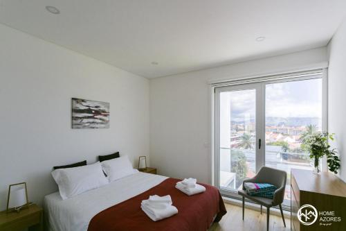 um quarto com uma cama e uma grande janela em Home Azores - Casas da Ladeira em Ponta Delgada