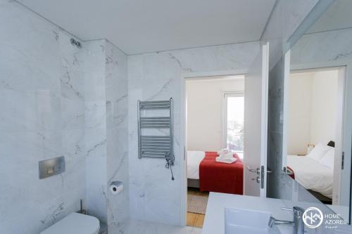 a bathroom with a sink and a toilet and a bedroom at Home Azores - Casas da Ladeira in Ponta Delgada