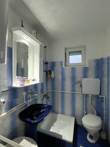 a blue tiled bathroom with a toilet and a sink at Sunny Funny House in Čačak