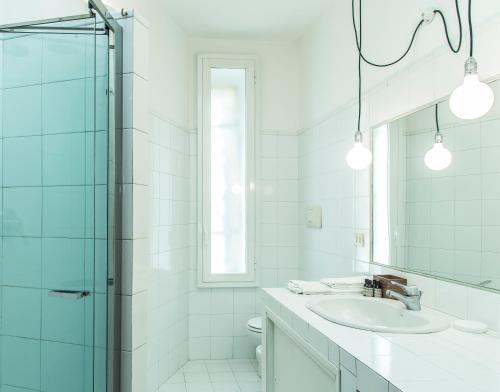 bagno bianco con lavandino e specchio di Brera Apartments in Porta Romana a Milano